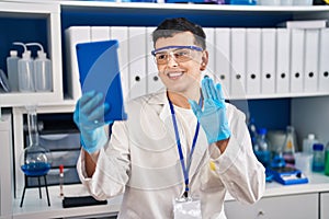 Non binary person working at scientist laboratory using tablet looking positive and happy standing and smiling with a confident