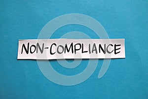 Non compliance  text words typography written on paper against blue background  life and business motivational inspirational