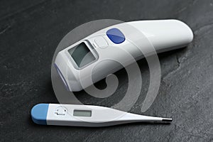 Non-contact infrared and digital thermometers on slate background