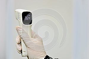 Non contact infrared forehead digital thermometer held by a medical personnel with right hand
