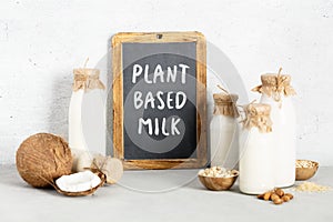 Non dairy plant based milk in bottles, ingredients and chalkboard with Plant based milk lettering on light background