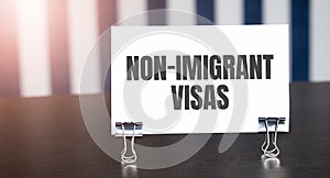 Non-imigrant visas sign on paper on dark desk in sunlight. Blue and white background photo