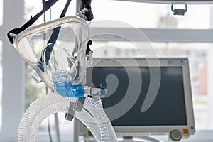 Non-invasive ventilation face mask, on background medical ventilator in ICU in hospital