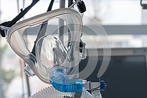 Non-invasive ventilation face mask, close up view, on background medical ventilator in ICU in hospital