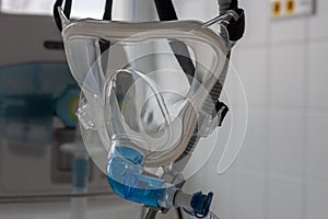 Non-invasive ventilation face mask, close up view, on background medical ventilator in ICU in hospital