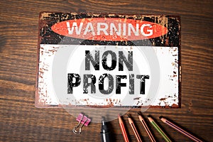 Non Profit Concept. Warning sign with text on wood texture background