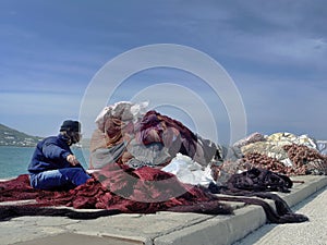Non recognize fisherman preparing several tools of fishing nets or fishing gear and rope, colorful trawler, seine and surrounding