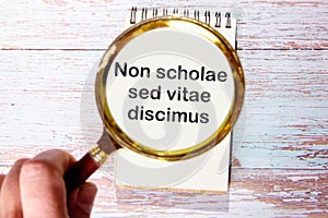 Non scholae sed vitae discimus It is translated from Latin as We study not for school, but for life. through a magnifying glass on photo