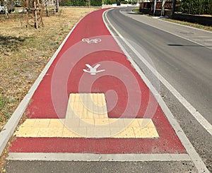 Non slip tiles at the end of a red concrete lane for bicycles and pedestrian along the road.