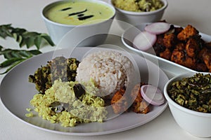 Non vegetarian meals prepared in Kerala style. The serving includes boiled red rice, stir fried onions with coconut, tempered