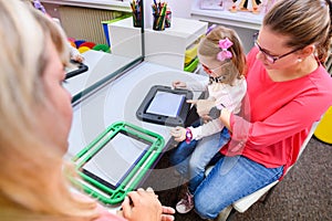 Non-verbal girl living with cerebral palsy, learning to use digital tablet device to communicate. photo