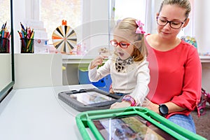 Non-verbal girl living with cerebral palsy, learning to use digital tablet device to communicate. Speech-generating devices. photo