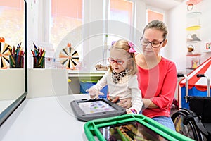 Non-verbal girl living with cerebral palsy, learning to use digital tablet device to communicate.