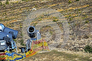 non-working snow generator on a slope without snow gear at a resort on a sunny day.