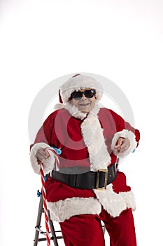A nonagenarian in a Santa Claus costume laughing and sitting on a walker.