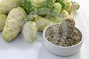 Noni fruit or Morinda Citrifolia with noni powder in ceramic bowl and wooden spoon on the white background, it is good source of