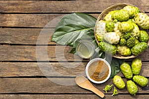 Noni fruit and noni in the basket with noni juice and noni powder on wooden table.Top view