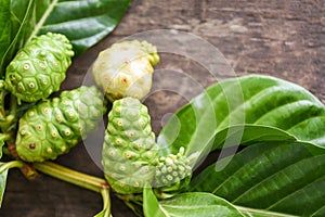 Noni fruit on wooden background - fresh ripe and raw noni leaf , Great morinda Noni or Morinda citrifolia