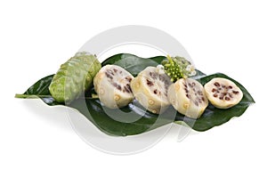 Noni fruits on green leaves and isolated on white background