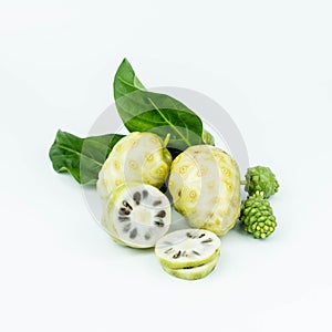 Noni or Morinda Citrifolia fruits with sliced and green leaf on white background