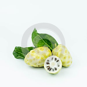 Noni or Morinda Citrifolia fruits with sliced and green leaf on white background