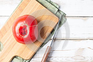 Nonstandard ugly tomato on a kitchen Board on a natural wooden table photo