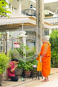 Asian woman is sitting and respecting Buddhist monks after offering food to monks, at front home in the morning, Monk wearing a