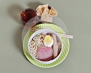 Noodle dumplings in a bowl with beef, egg and sausage toppings.