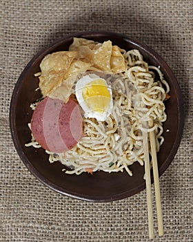 Noodle dumplings in a bowl with beef, egg and sausage toppings.