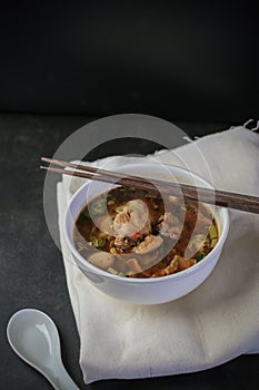 Noodle with Kao Lao Moo Toon. Thai pork stew soup in white bowl on black table. photo