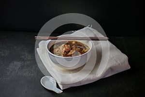 Noodle with Kao Lao Moo Toon. Thai pork stew soup in white bowl on black table photo