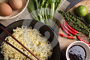 Noodles in black bowl garnished on kitchen table