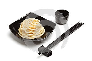 Noodles in black ceramic dish stand on white table background wi