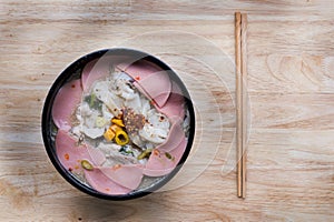 Noodles in a bowl with ham and pork served