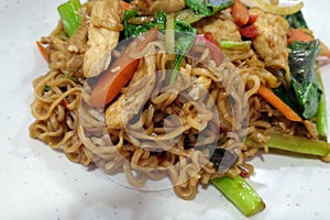 Noodles, chicken and vegetables on white plate