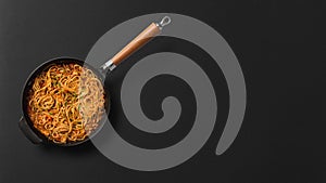 Noodles in pan on black background top view stock photograph