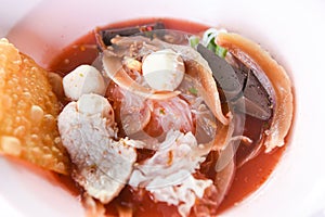 Noodles with seafood on red soup - hot and spicy thai food noodle squid pork fish ball morning glory crispy wonton skin pork and