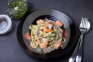Noodles with seafood, sun-dried tomatoes, capers and red onions. Homemade pasta with shrimp, salmon trout and pesto sauce.