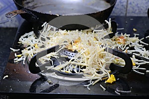 Noodles spilled all over gas stove top and burner due to broken handle of pan, view of pan handle broken in background