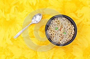 Noodles and vegetables with spoon in black bowl