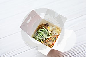 Noodles in a white box on a wooden background close up shot