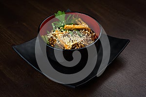 Noodles wok with chicken in a plate on a wooden table