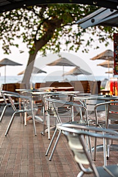 Nook of street cafee with several metal chairs and tables near sea. photo