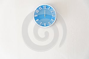Noon or midnight time with 12:00 clock on white concrete wall in