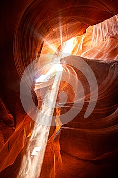 Noon in a red-orange Antelope Canyon. A thin ray of sunlight illuminates the sandy bottom of the canyon