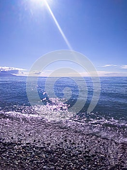 Noon on the seashore, sea stones, a ray of sun falls from above