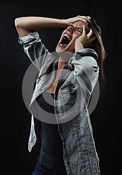 Noooo Leave me alone. A young woman screaming uncontrollably while isolated on a black background.