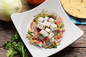 Nopal cactus salad with cheese on wooden background. Mexican food