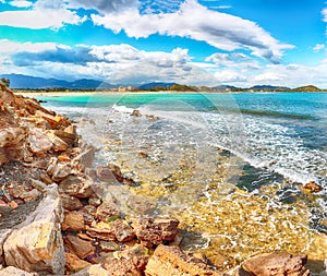 The Nora bay and beach, the medieval Sant\'Efisio church near the shore and mountains in the background