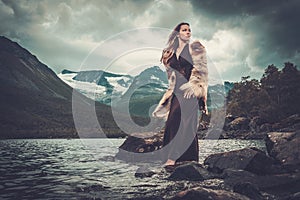Nordic goddess in ritual garment near wild mountain lake in Innerdalen valley.